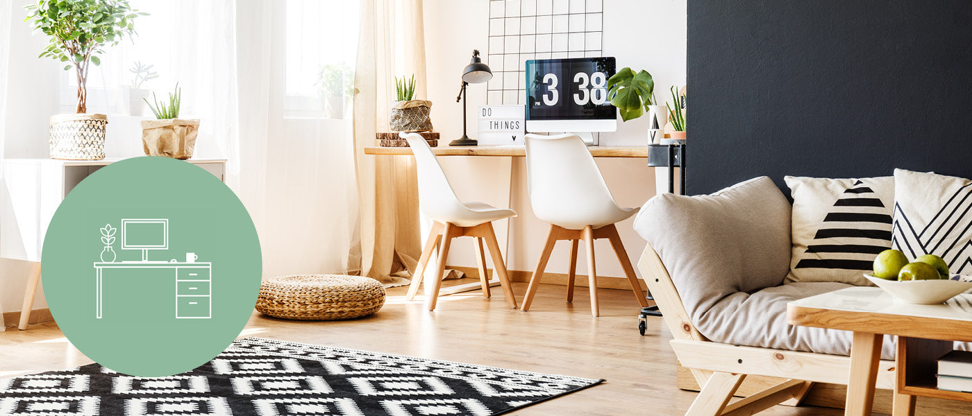 Modernes Wohnzimmer mit Arbeitsbereich, einem Holzschreibtisch, zwei weißen Stühlen, einer schwarzen Uhr und Pflanzen. Im Vordergrund stehen ein gemütliches Sofa, ein gemusterter Teppich und dekorative Kissen. Ein grünes Symbol ist darüber gelegt.