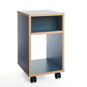 Das „Regal auf Rollen“ von buchenblau ist ein kompakter rollbarer Beistelltisch mit zwei Ablageflächen, der durch sein helles Holzgestell und die blauen Paneele besticht. Vier schwarze Rollen sorgen für leichte Mobilität und viel Stauraum.