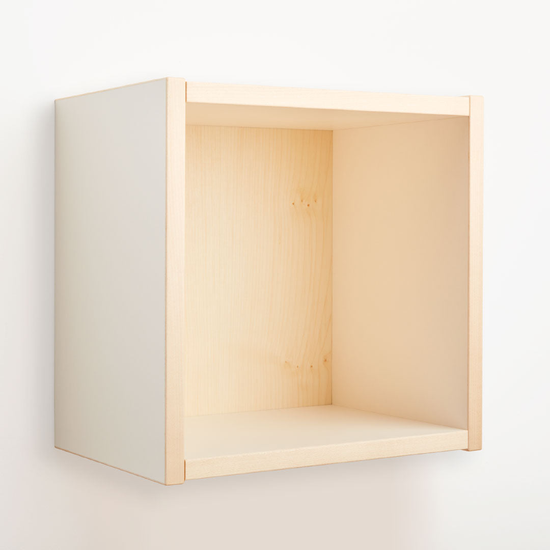 Ein buchenblauer Regalwürfel farbig 36 x 36 cm, mit einem minimalistischen offenen Würfeldesign mit klaren Linien und einem hellen Holzfinish, wird an einer schlichten weißen Wand montiert und sorgt für einen einfachen, modernen Look.