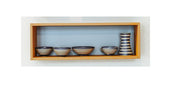 Der Wandregalwürfel Esche - L von buchenblau präsentiert wunderschön vier kleine Keramikschalen und eine blau-weiß gestreifte Vase mit seinem natürlichen Eschenholz-Finish vor dem charakteristischen buchenblau-Hintergrund der Marke.