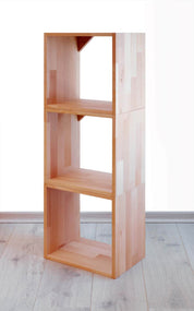 Ein Holzbücherregal von buchenblau, bestehend aus vier vertikal gestapelten Regalwürfeln Massivholz 36 x 36 cm, besticht durch ein schlichtes, modernes Design. Es steht auf einem hellen Holzboden vor einem schlichten weißen Hintergrund.