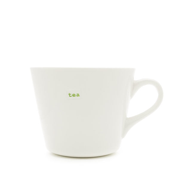 Eine weiße Teetasse aus Keramik mit kleinem Henkel, auf deren einer Seite die Worte „Guten Morgen“ in Grün aufgedruckt sind, was an ein Design von Keith Brymer Jones erinnert. Die Tasse „Guten Morgen“ (350 ml) steht auf einem schlichten weißen Hintergrund.