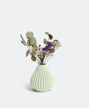 Die Vase „Raindrop“ in Salbei von nevalu besticht durch ein hellgrünes, geripptes Design und präsentiert ein wunderschönes Arrangement aus Eukalyptusblättern, Schleierkraut und violetten Blüten vor einem hellen Hintergrund. Dieses Stück ist ein Beispiel für nachhaltiges Design durch die Verwendung von recyceltem Kunststoff.