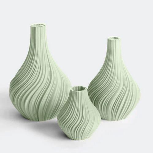 Die Vasenkollektion „Swirl“ von nevalu umfasst drei salbeifarbene Vasen, die jeweils aus recyceltem Kunststoff hergestellt sind. Sie zeichnen sich durch unterschiedliche Größen und eine strukturierte, wellige Oberfläche aus, wodurch ihr umweltfreundliches 3D-Druckdesign sich wunderschön vom weißen Hintergrund abhebt.