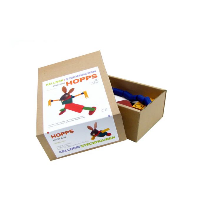 Ein teilweise geöffneter Karton mit der Aufschrift "Häslein Hopps - Kellner Steckfigur" von buchenblau offenbart im Inneren bunte Spielzeugteile und die Abbildung einer aus den Teilen zusammengesetzten Hasenfigur auf der Verpackung.