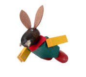 Das Häslein Hopps - Kellner Steckfigur von buchenblau ist ein Holzspielzeughase mit braunen Ohren, grünem Körper, roten Beinen, gelben Armen und rotem Halsband, der wie fliegend vor einem weißen Hintergrund posiert.