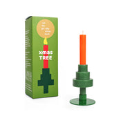 Die Party Candle Xmas Tree von not the girl besteht aus einem grünen, geometrischen Baum-Kerzenhalter und einer orangefarbenen Stearin-Wachs-Kerze. Die Box verfügt über Produkt-Grafiken und die Phrase "nicht das Mädchen, das viel vermisst.