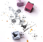 Eine skurrile Tuscheillustration zeigt Akrobaten auf Discokugeln, mit Stern- und Punktmustern. Daneben sind drei buchenblaue Ministempel - Adventskalender - zwei rosa und ein blauer - auf dem weißen Papier platziert.
