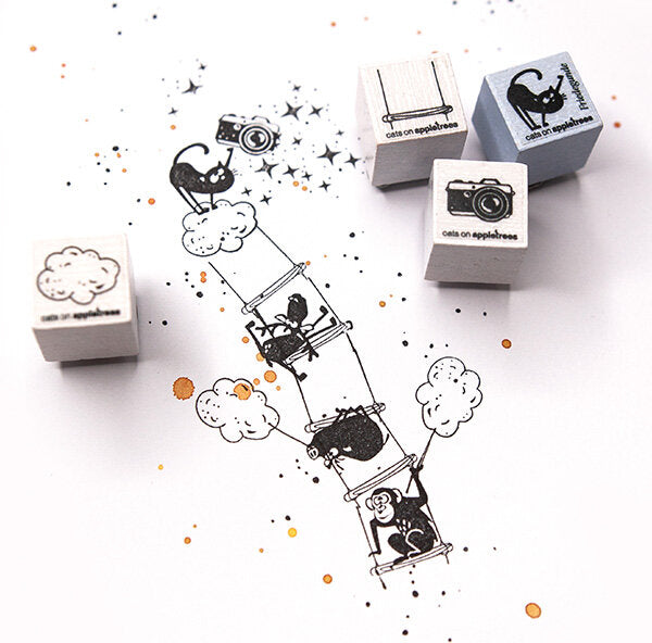 Vier buchenblaue Ministempel - Adventskalender-Stempel mit verspielten Katzenmotiven sind neben gestempelten Katzenbildern mit Kameras und Sternen auf weißem Papier abgebildet - eine entzückende Überraschung für jeden Adventskalender!.