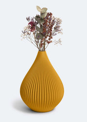 Eine senfgelbe, gerippte Vase „Raindrop“ in Ocker von nevalu, die einen Strauß getrockneter Blumen mit Lavendel, Schleierkraut und Eukalyptus vor einem schlichten weißen Hintergrund hält. Die Vase hat eine Tropfenform mit vertikalen Rillen und wird im 3D-Druckverfahren aus recyceltem Kunststoff hergestellt.