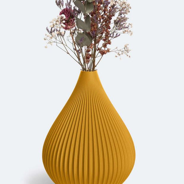 Eine senfgelbe, gerippte Vase „Raindrop“ in Ocker von nevalu, die einen Strauß getrockneter Blumen mit Lavendel, Schleierkraut und Eukalyptus vor einem schlichten weißen Hintergrund hält. Die Vase hat eine Tropfenform mit vertikalen Rillen und wird im 3D-Druckverfahren aus recyceltem Kunststoff hergestellt.